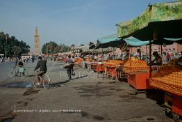 Image du Maroc Professionnelle de  L'espace réservé aux chariots des vendeurs de jus d'oranges et de pamplemousses, bien alignés à non plus finir sur La mythique place Jemaa El Fana, le lieu incontournable de Marrakech de la ville touristique du Maroc, au fond le minaret de la Koutoubia, Jeudi 19 Mai 1988. (Photo / Abdeljalil Bounhar)